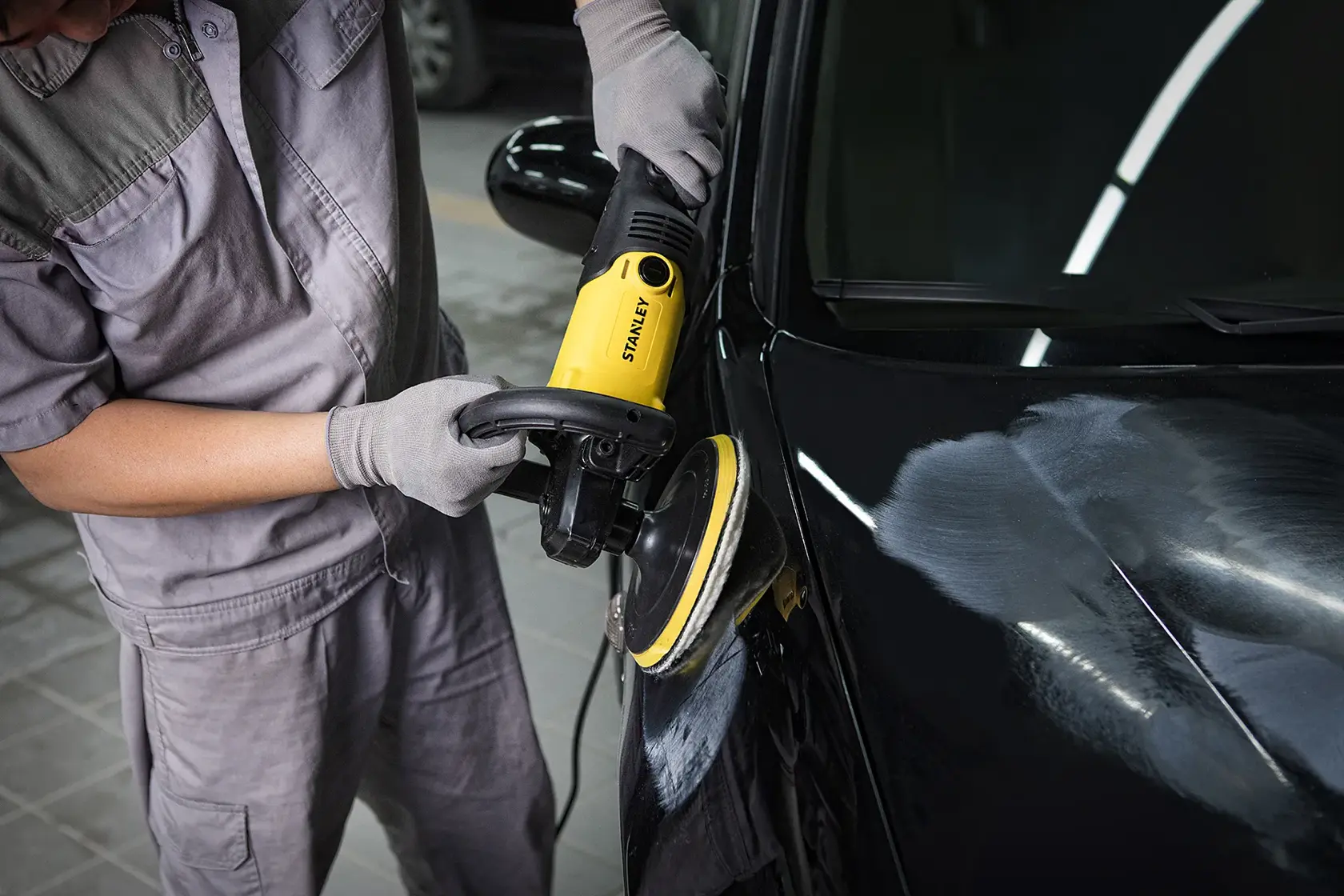 STANLEY SP137 pulidora amarilla para autos en uso, cerca mostrando pulido de capó vehículo negro.