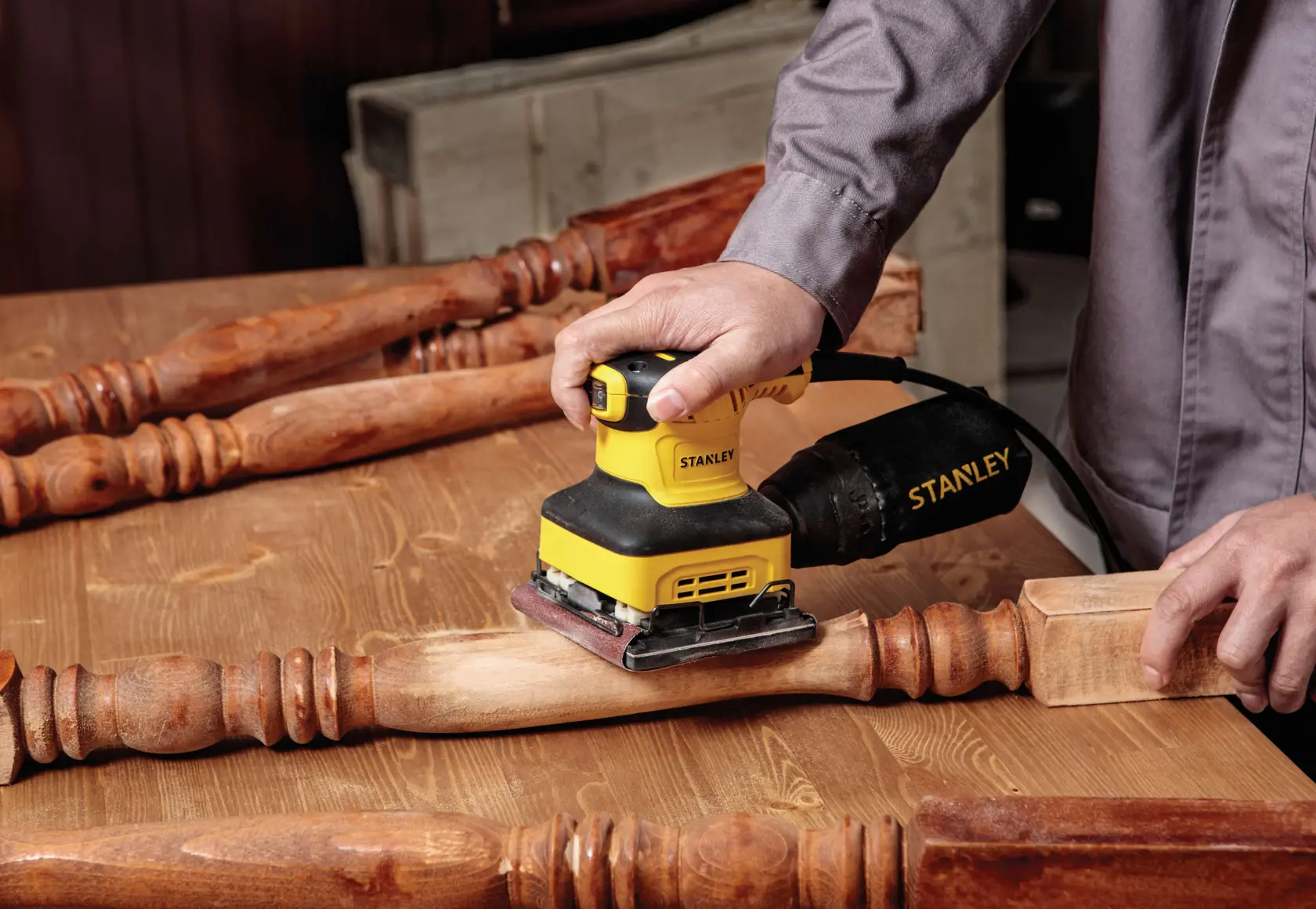Stanley SS24-B3 lijadora usada en una pata de mesa de madera, vista cercana en taller.