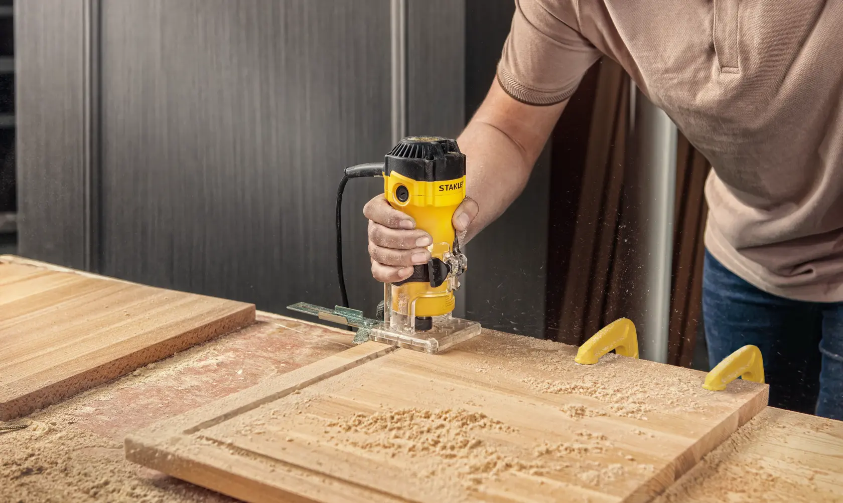 STANLEY ST55-B2 router para madera usado en tabla, cuerpo amarillo, entorno de taller.