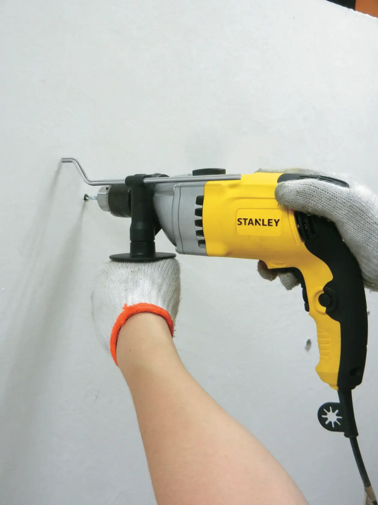 Stanley STDH8013 taladro con cable amarillo y negro en uso sobre pared blanca, categoría herramienta eléctrica, ángulo lateral.