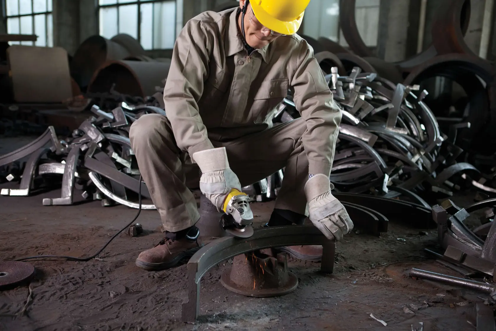 STANLEY STGS8115 amoladora angular en uso por trabajador con equipo de protección, esmerilando metal en entorno industrial.