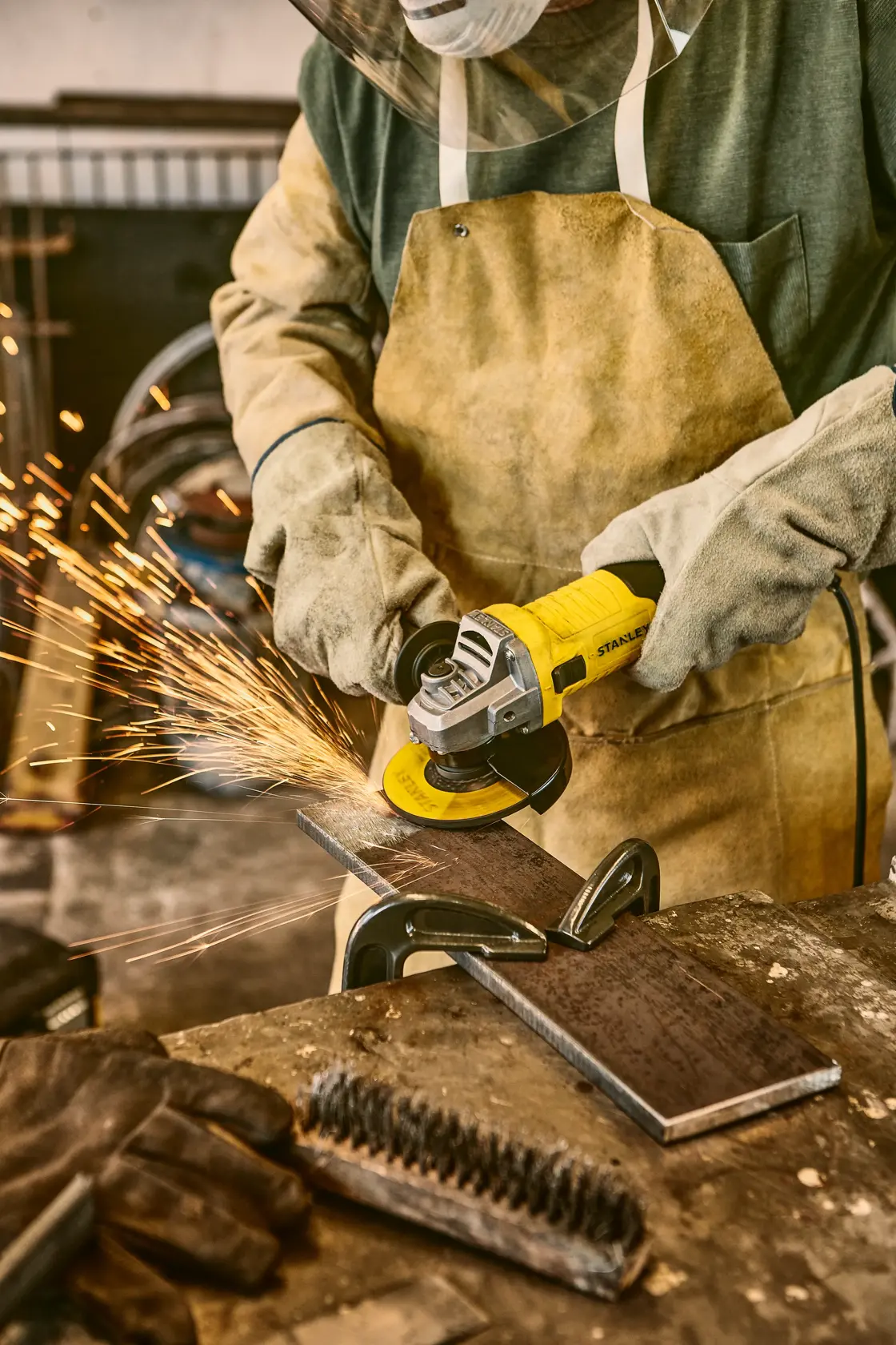 Stanley stgs9115 amoladora angular en uso, trabajador cortando metal con equipo de seguridad, taller.