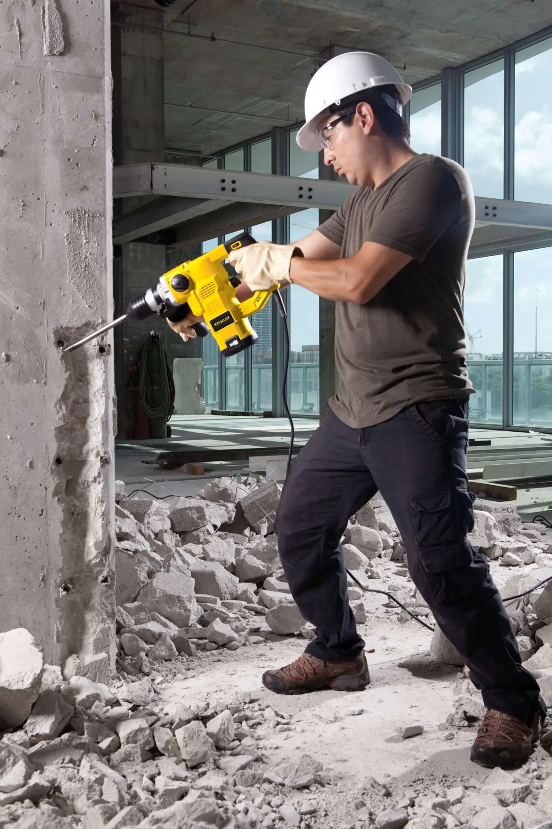 Taladro percutor STANLEY STHR1232K utilizado en una pared de concreto en obra, vista lateral.