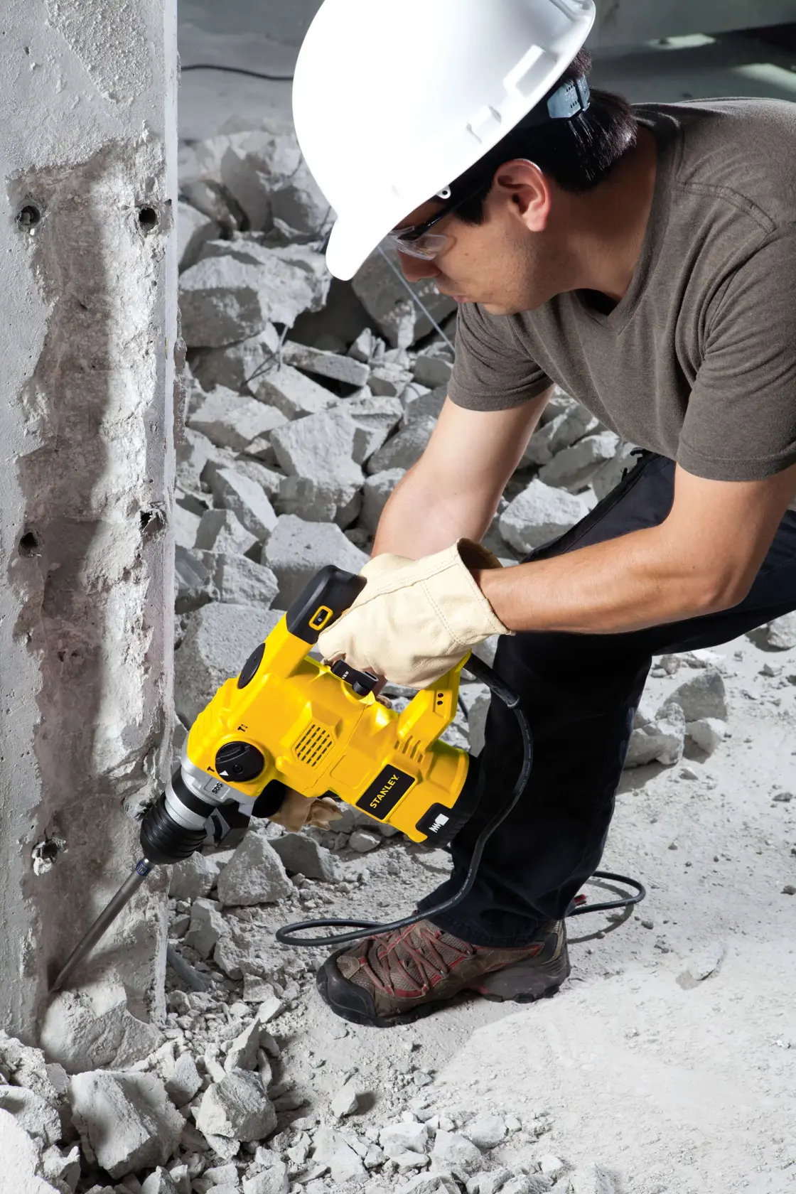 Fotografía de trabajador usando martillo demoledor STANLEY STHR1232K en pared de concreto en obra.