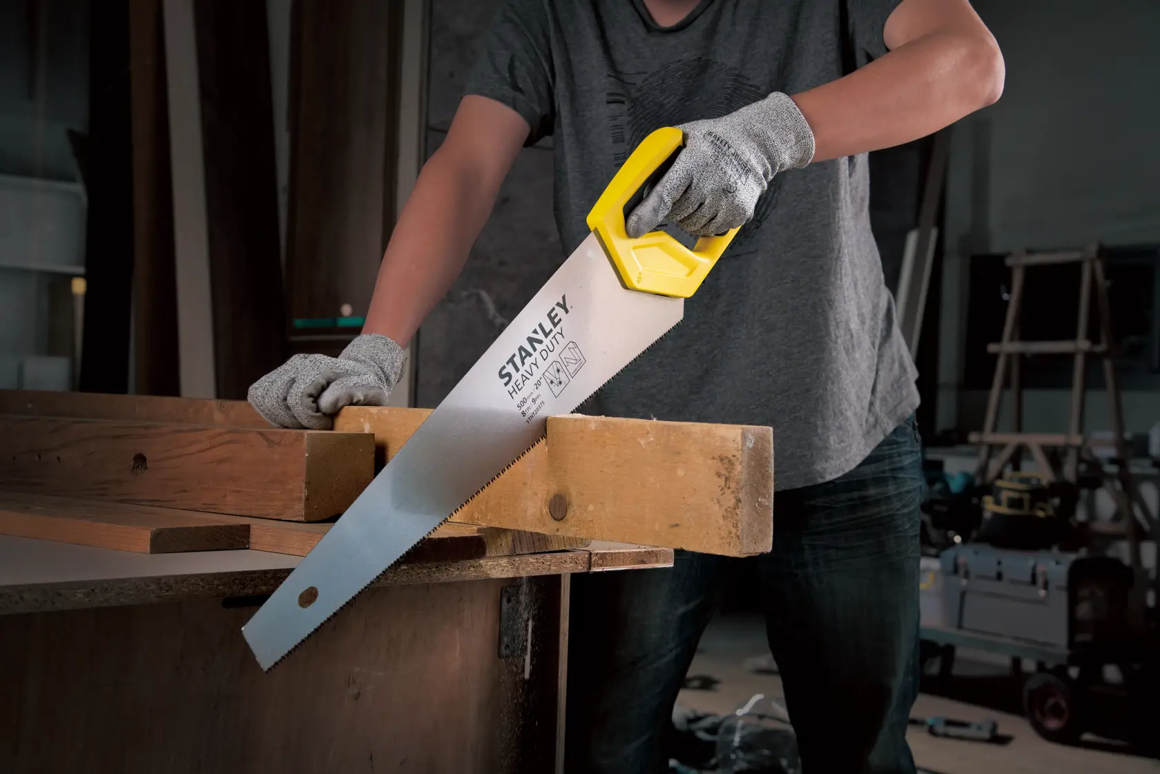 Fotografía de sierra manual STANLEY STHT20375-LA con mango amarillo cortando madera, producto en uso en taller.