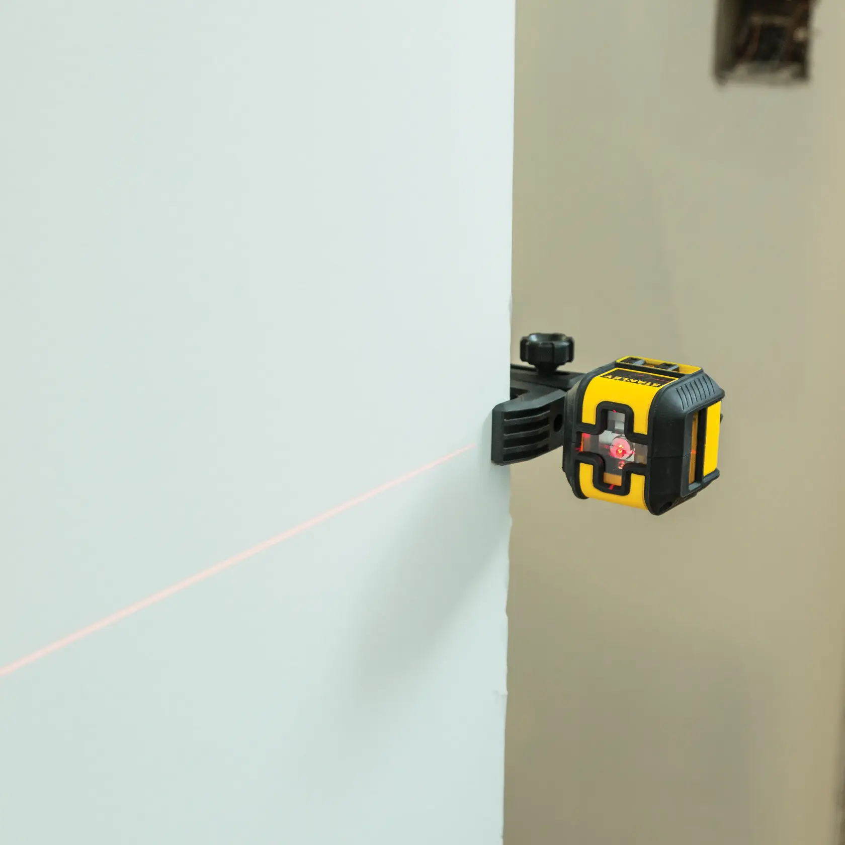 STANLEY STHT77498 herramienta de nivel láser montada en la pared, con línea láser roja horizontal.