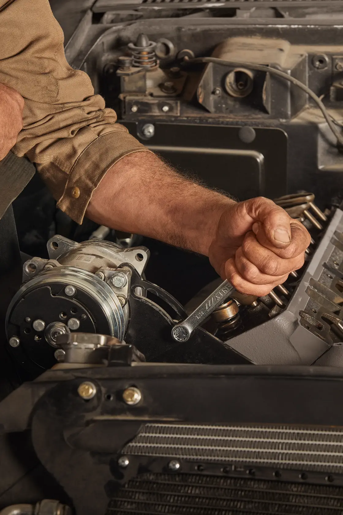 Llave STANLEY STMT72834 sostenida por un mecánico en el compartimento del motor de un automóvil, vista cercana.