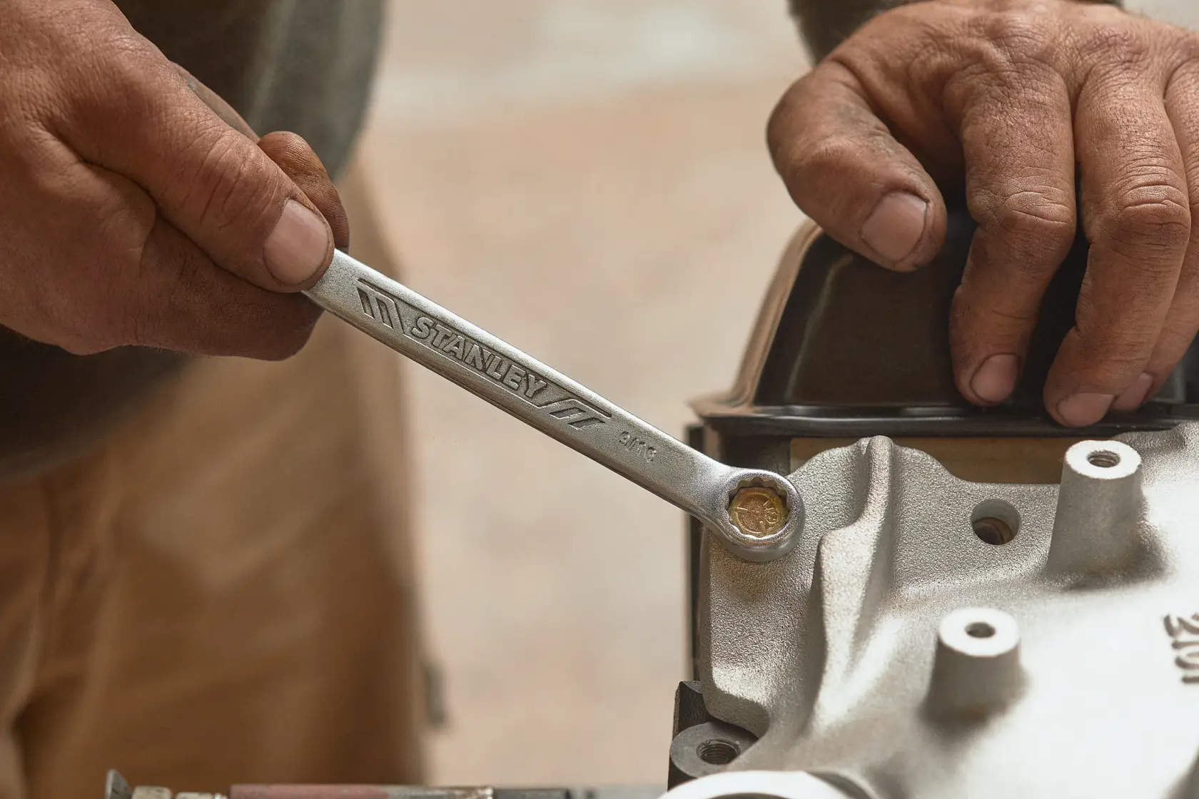 Llave STANLEY STMT72834 en uso, fotografía en primer plano de mano girando perno en maquinaria.