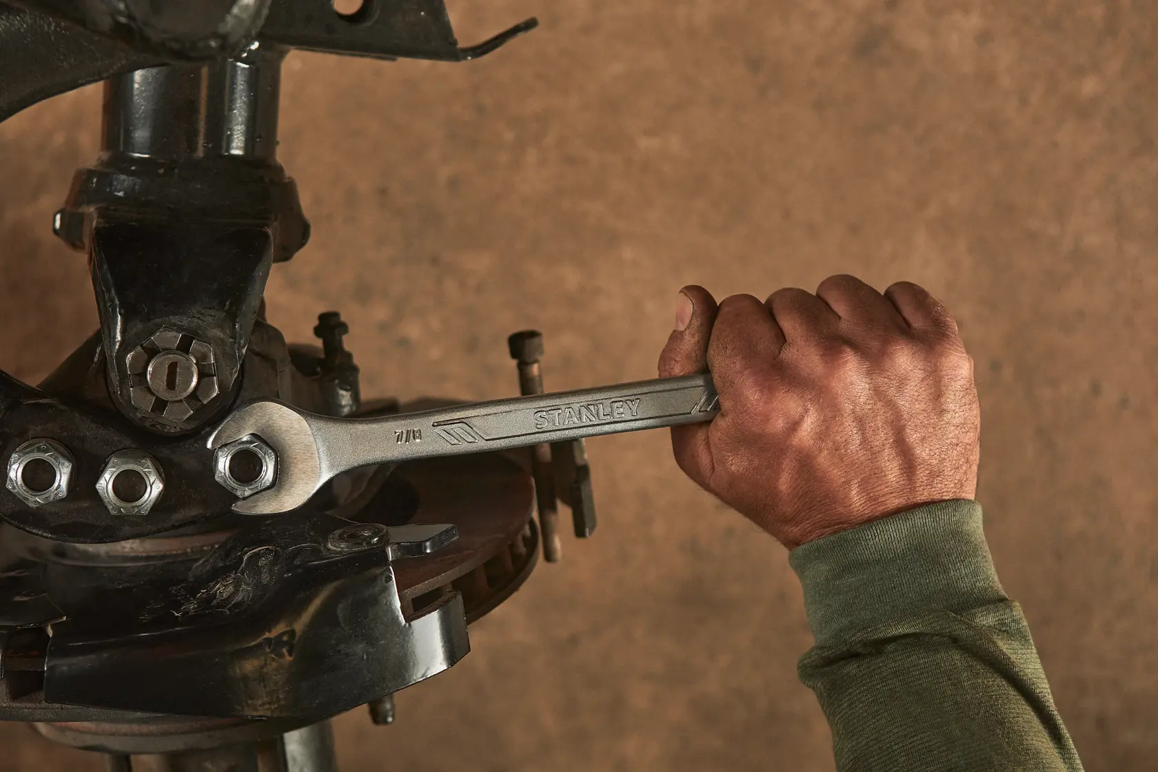 Fotografía de una mano usando una llave STANLEY STMT72839 en un perno de suspensión de automóvil.