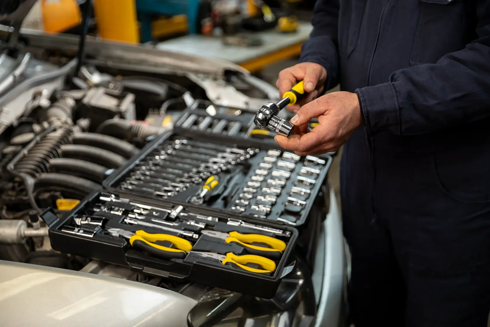 STANLEY STMT81243-LA juego de herramientas mecánicas con mangos amarillos y dados en estuche abierto sobre motor de auto.