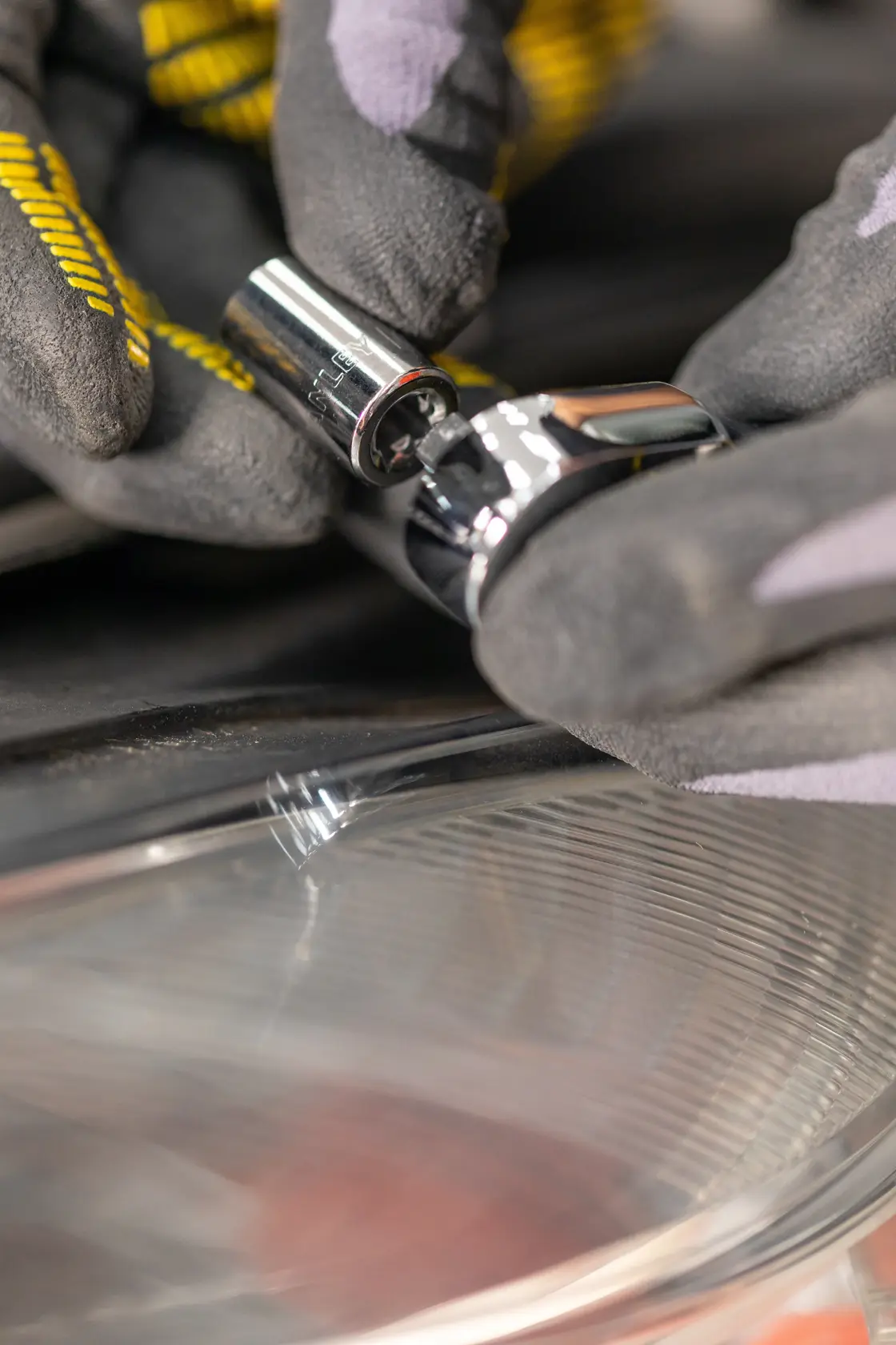 Llave de vaso STANLEY STMT82828-LA usada con un trinquete, primer plano de manos enguantadas en entorno automotriz.
