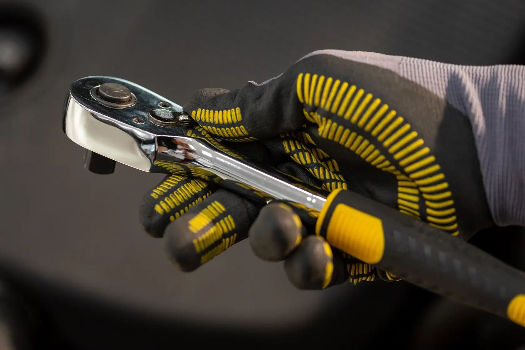 STANLEY STMT82830-LA trinquete sostenido por mano enguantada, toma cercana con detalle de agarre negro y amarillo.