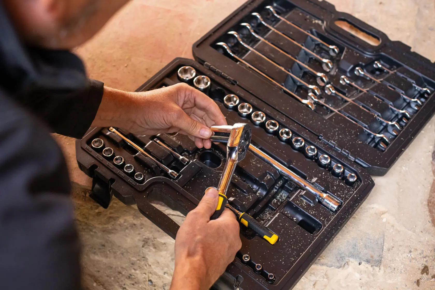 Fotografía del juego de dados y llaves STANLEY STMT82832-LA en estuche negro, persona eligiendo una carraca.