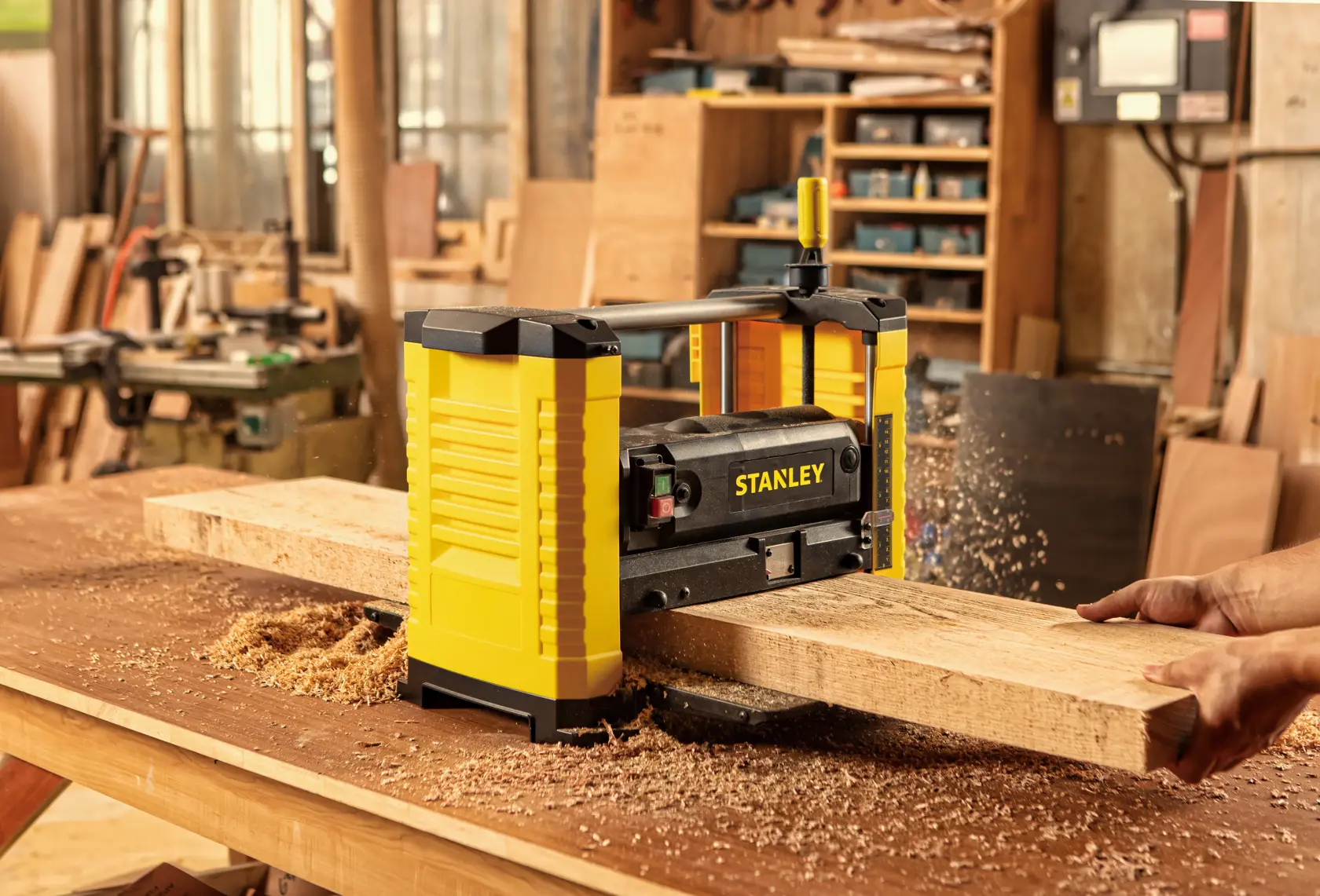 Cepillo STANLEY STP18-B2 en uso, amarillo y negro, virutas de madera en banco de trabajo en taller.