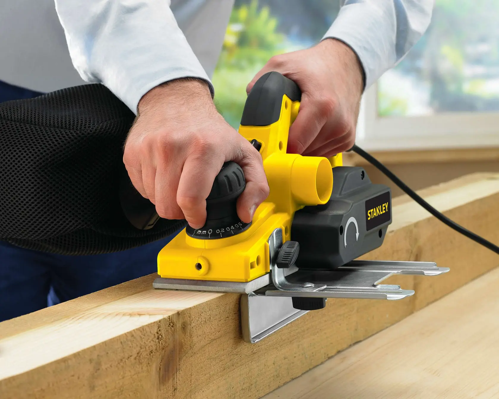 Cepillo eléctrico STANLEY STPP7502-B2 con mango negro en uso sobre madera, ángulo de primer plano.