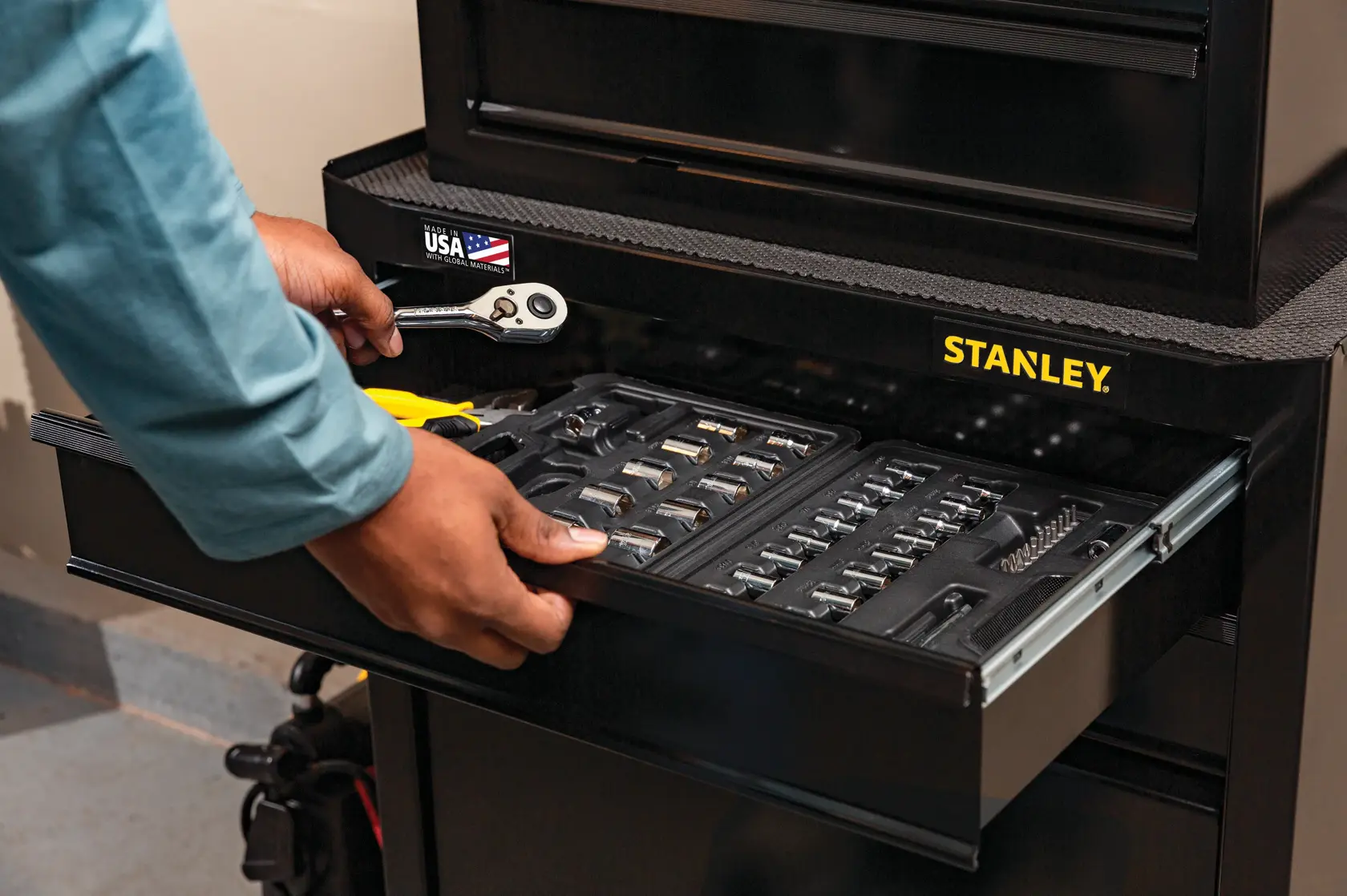 Foto del cajón del gabinete de herramientas STANLEY STST22656BK abierto, mostrando juego de dados, trinquete y pinzas organizados.