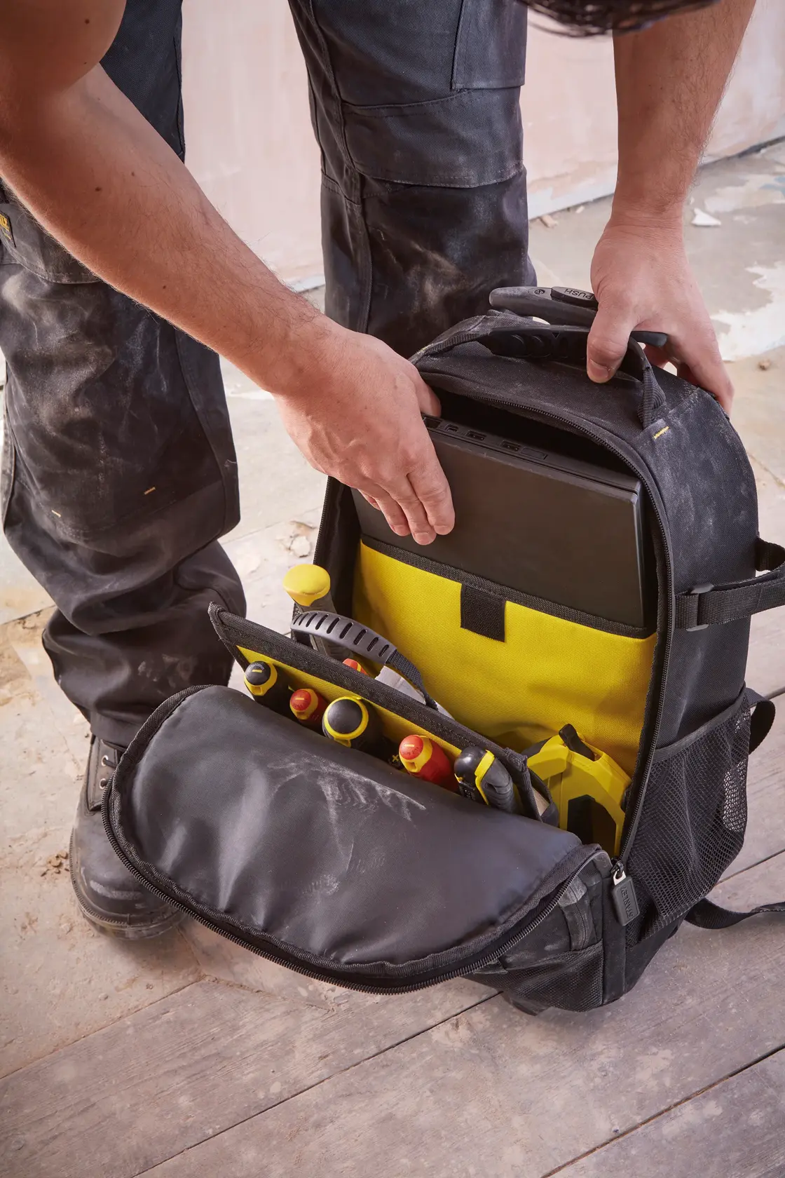 STANLEY STST83307-1 mochila para herramientas con interior amarillo, bolsillo abierto muestra herramientas y tableta.