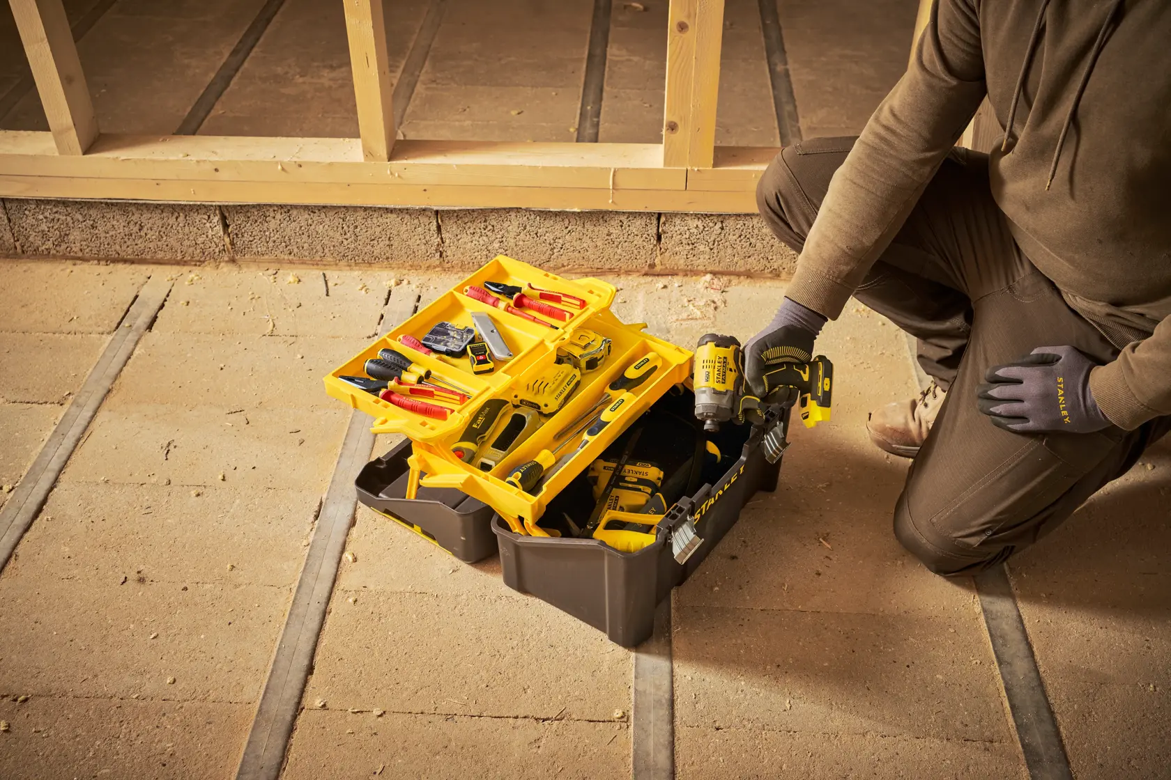 Caja de herramientas STANLEY STST83397-1 abierta con herramientas variadas y taladro en obra.