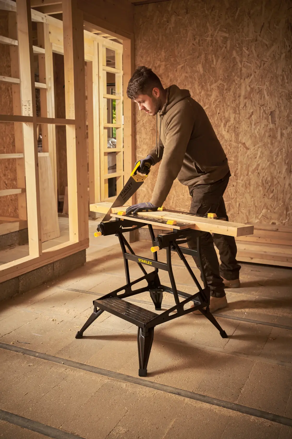Banco de trabajo STANLEY STST83400-1 en uso, sosteniendo madera para serrar en una obra.