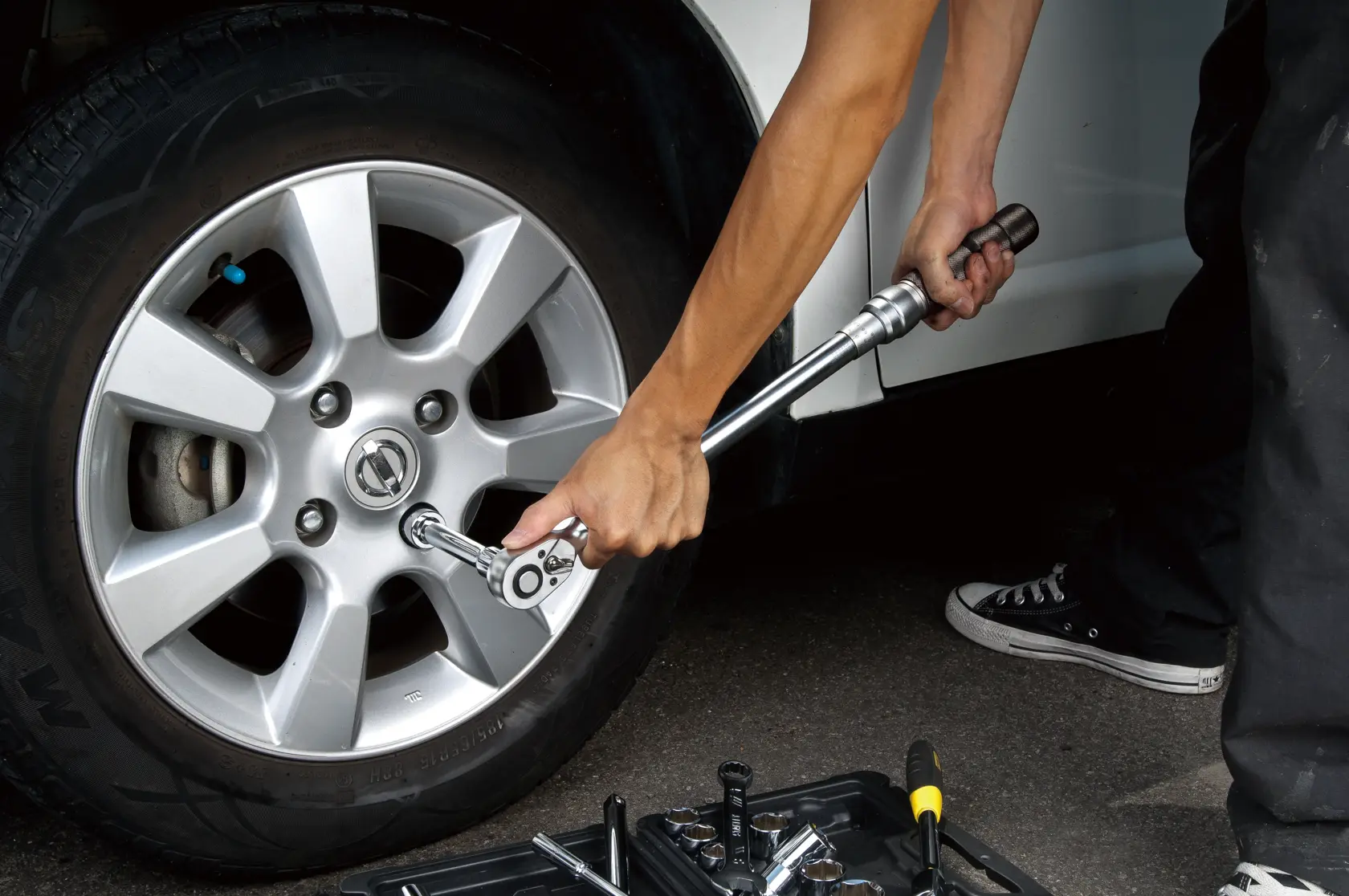 Fotografía STANLEY Torque_wrench mostrando llave de torsión plateada ajustando tuercas de rueda de auto al aire libre.