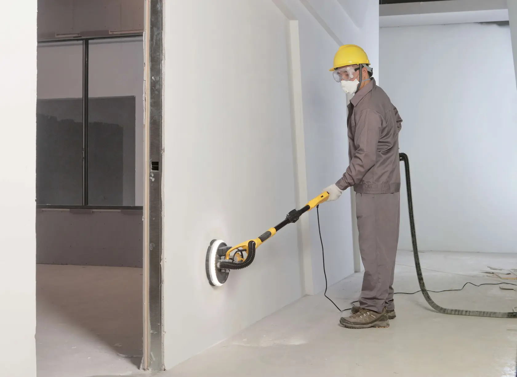 STANLEY SW75-BR lijadora de paneles de yeso utilizada por un trabajador en una pared blanca, fotografía lateral.